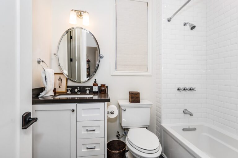 Modern bathroom with white tub, toilet, sink, and mirror