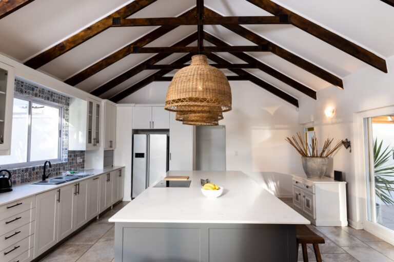 Lighting equipment hanging in a row from mansard roof over kitchen island in modern kitchen. Copy space, white, unaltered, home and interior decoration concept.