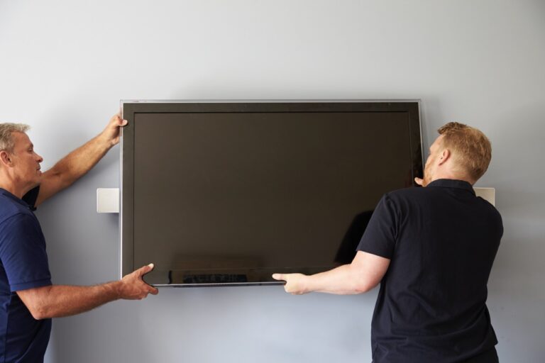 Two Men Fitting Flat Screen Television To Wall